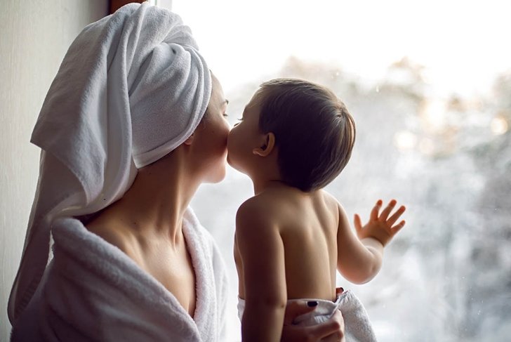 mom and son sitting by the window on a wide windowsill in a bathrobe after a bath