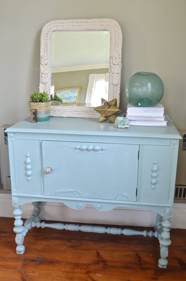 Knotted rope mirror display on blue sideboard.